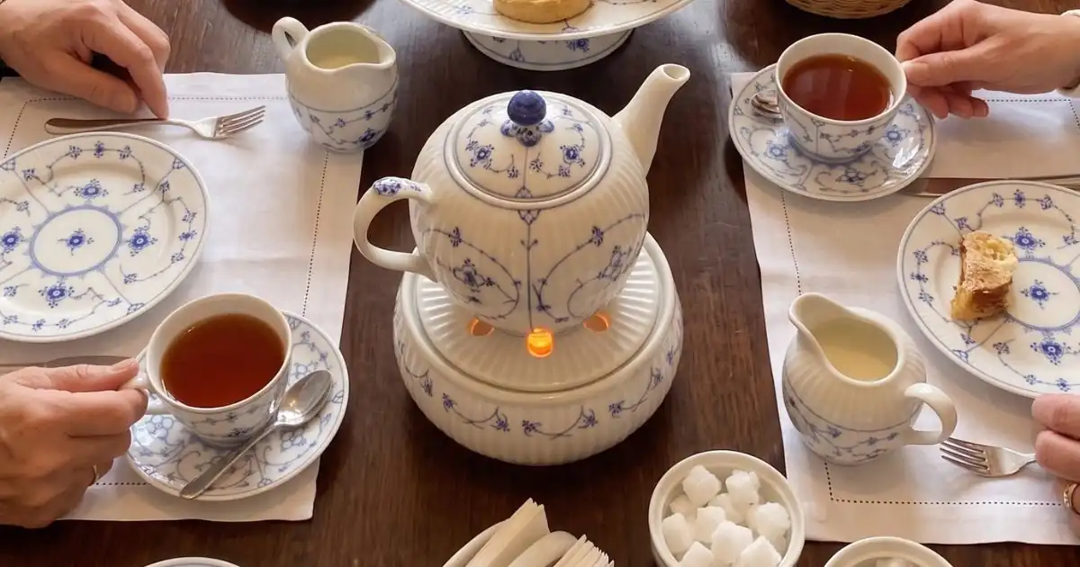Traditionelle ostfriesische Teetafel mit blau-weißem Porzellanservice, Stövchen, Kluntje und Sahnekännchen.