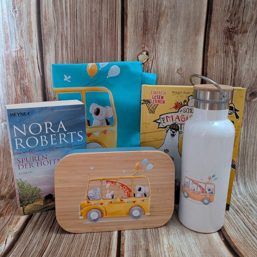 Gewinnspiel-Set aus Büchern, einer Brotzeitbox, einer Trinkflasche und einer Tasche mit tierischen Motiven auf Holzgrund.