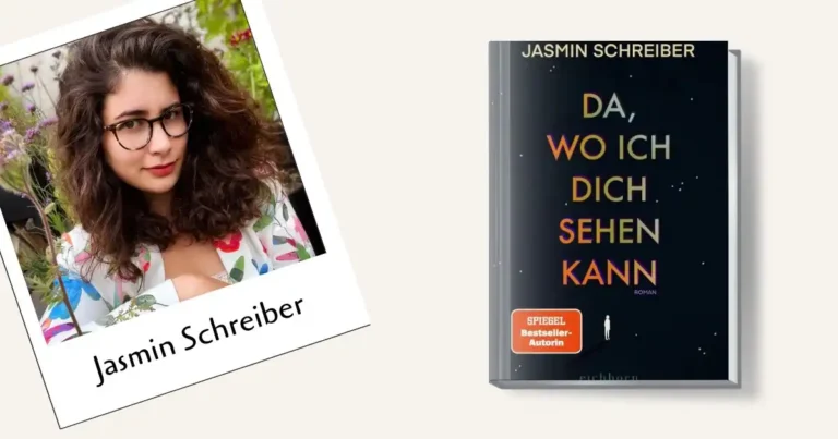 Ein Porträt von Jasmin Schreiber, die mit langen, dunklen Locken und einer Hornbrille direkt in die Kamera lächelt. Sie trägt eine weiße Jacke mit einem auffälligen, bunten floralen Muster. Der Hintergrund ist ein unscharfer Garten mit vielen grünen Pflanzen und lila Blüten. Ihre linke Hand mit einem Ehering ist sichtbar.